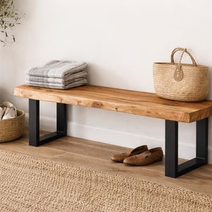 Può includere: Panca in legno con finitura naturale e gambe in metallo nero. Un cesto intrecciato, una coperta piegata e una borsa di paglia sono sulla panca. Un vaso di fiori e un cesto di scarpe sono nelle vicinanze. Scarpe in pelle marrone.