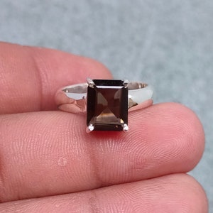 May include: A silver ring with a rectangular, dark brown gemstone.