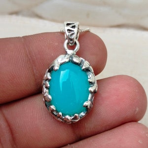 May include: A silver pendant with a turquoise blue oval gemstone set in a detailed silver frame.