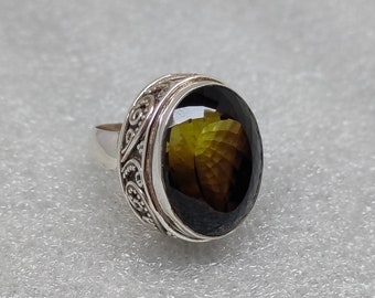 May include: A silver ring with an oval-shaped, dark green gemstone set in a detailed, ornate silver band.