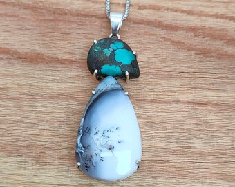 Pode incluir: Um colar de corrente de prata com um pingente com duas pedras. A pedra superior é um cabochão turquesa e verde, e a pedra inferior é uma ágata branca e cinza.
