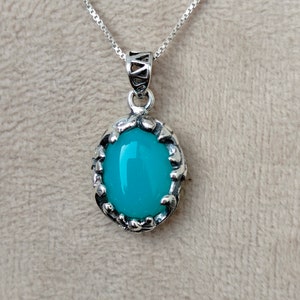 May include: A silver chain necklace with a pendant featuring a turquoise oval gemstone set in a silver filigree frame.