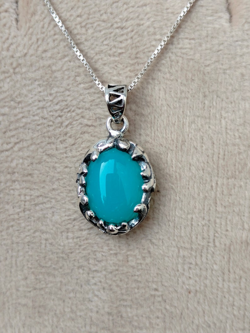 May include: A silver chain necklace with a pendant featuring a turquoise oval gemstone set in a silver filigree frame.