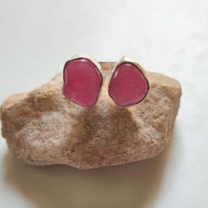 Peut inclure: Une bague en argent avec deux pierres pr&eacute;cieuses roses. Les pierres pr&eacute;cieuses sont de forme irr&eacute;guli&egrave;re et ont un aspect brut et naturel.