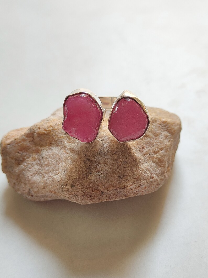 Peut inclure: Une bague en argent avec deux pierres pr&eacute;cieuses roses. Les pierres pr&eacute;cieuses sont de forme irr&eacute;guli&egrave;re et ont un aspect brut et naturel.