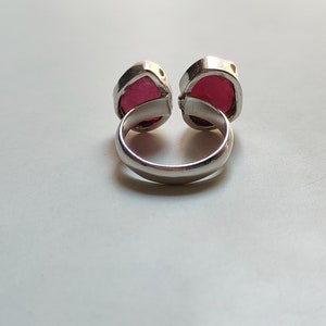 Peut inclure: Une bague en argent avec deux pierres pr&eacute;cieuses rouges. La bague est con&ccedil;ue pour &ecirc;tre port&eacute;e sur le majeur.