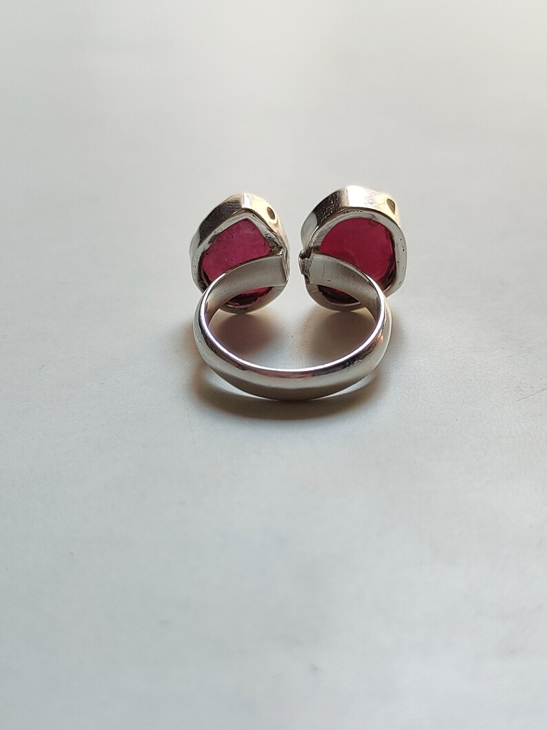Peut inclure: Une bague en argent avec deux pierres pr&eacute;cieuses rouges. La bague est con&ccedil;ue pour &ecirc;tre port&eacute;e sur le majeur.
