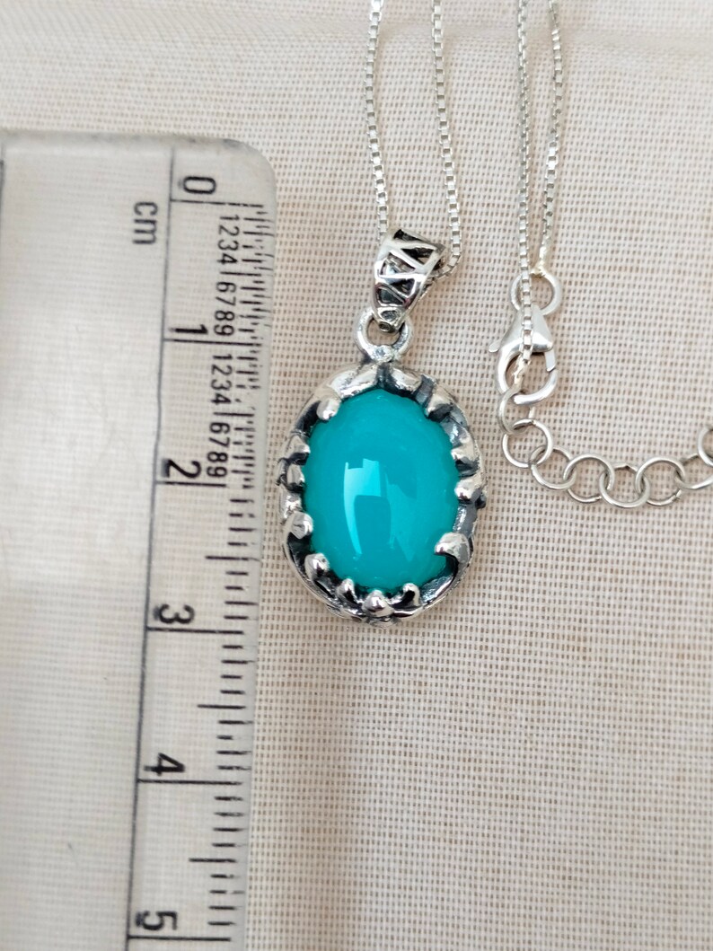 May include: A silver chain necklace with a pendant featuring a turquoise oval gemstone set in a silver filigree frame.