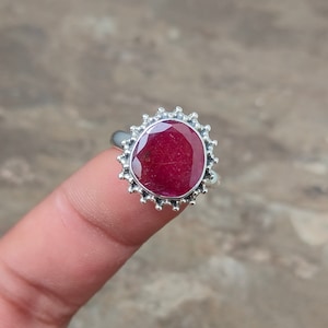 May include: A silver ring with a red oval gemstone set in a decorative silver bezel.
