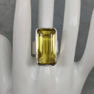 May include: A silver ring with a large, rectangular, yellow citrine gemstone.