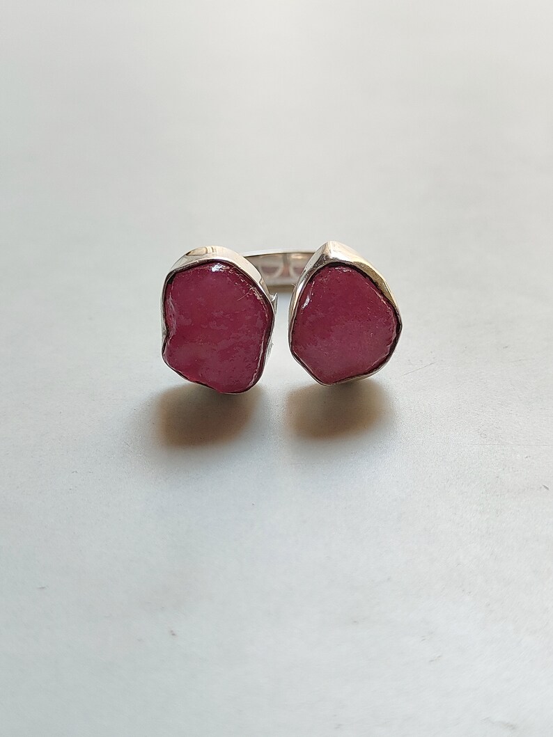 Peut inclure: Une bague en argent avec deux pierres pr&eacute;cieuses roses. Les pierres pr&eacute;cieuses sont de forme irr&eacute;guli&egrave;re et ont un aspect brut et naturel.