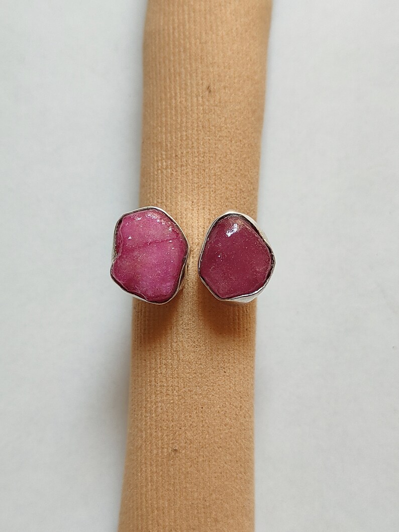 Peut inclure: Une bague en argent avec deux pierres pr&eacute;cieuses roses. Les pierres pr&eacute;cieuses ont une forme irr&eacute;guli&egrave;re et un aspect brut et naturel.