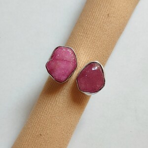Peut inclure: Deux bagues en argent serties de pierres pr&eacute;cieuses roses. Les bagues sont sur une surface en tissu brun.