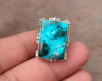 Könnte beinhalten: Ein silberner Ring mit einem rechteckigen Türkis-Edelstein. Der Edelstein hat ein wirbelndes Muster aus Blau, Grün und Weiß.