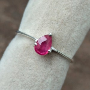 May include: A silver ring with a teardrop-shaped pink gemstone.
