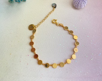 May include: A gold chain bracelet with a series of small, round, gold charms. The bracelet has a lobster clasp closure.