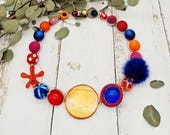 extravagante Kette mit Puschel, Püppchen, Muranoglas und Polarissperlen in kräftigen Farben