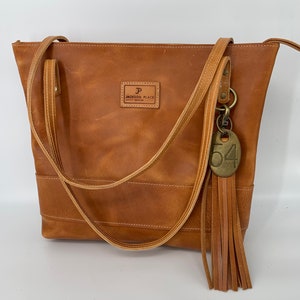 Jackson Place Collection - Bolso de mano grande Portofino clásico de piel color canela - Correa para bolso de mano marrón Bolso de mano Piel de vaca Latón dorado Etiqueta de vaca Borla Cremallera