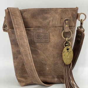 Bolso tipo cubo de piel gris: bandolera con borla y etiqueta de vaca