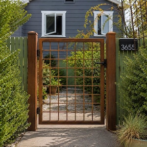 May include: A rectangular metal gate with a grid pattern, featuring a rusted brown finish and a black handle. The gate is mounted between two tall, square, rusted brown metal posts. A black rectangular mailbox with the white number 3655 is attached.