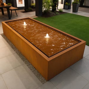 May include: A rectangular, rust-colored water fountain with two small water jets. The fountain is sitting on a light gray tiled patio.