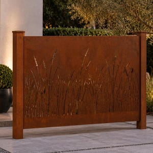 May include: A rectangular, rust-colored metal privacy screen featuring a laser-cut design of tall grasses. The screen is supported by two vertical posts on either side, creating a solid barrier with a textured, weathered finish.
