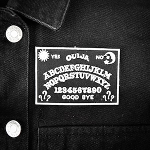 May include: Black and white ouija board patch with the words "YES", "OUIJA", "NO", "GOOD BYE", and question marks. The board also includes the alphabet, numbers 1-9 and 0.