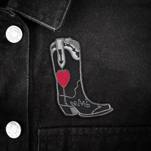 May include: A black denim jacket with a gray embroidered patch of a cowboy boot with a red heart on the side.