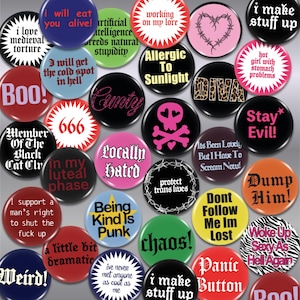 May include: A collection of circular pin-back buttons featuring various colours and text designs including phrases like I will eat you alive, Allergic To Sunlight, Stay Evil, Dump Him, Being Kind Is Punk, and other slogans in diverse fonts.