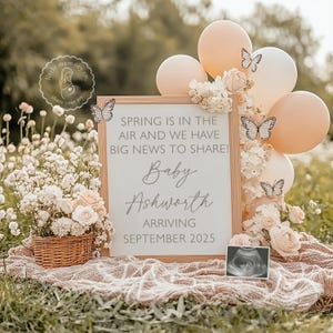 May include: A wooden sign with a white background and black text announcing a baby is arriving in September 2025. The sign is decorated with butterflies and flowers. The text reads "Spring is in the air and we have big news to share! Baby Ashworth Arriving September 2025".