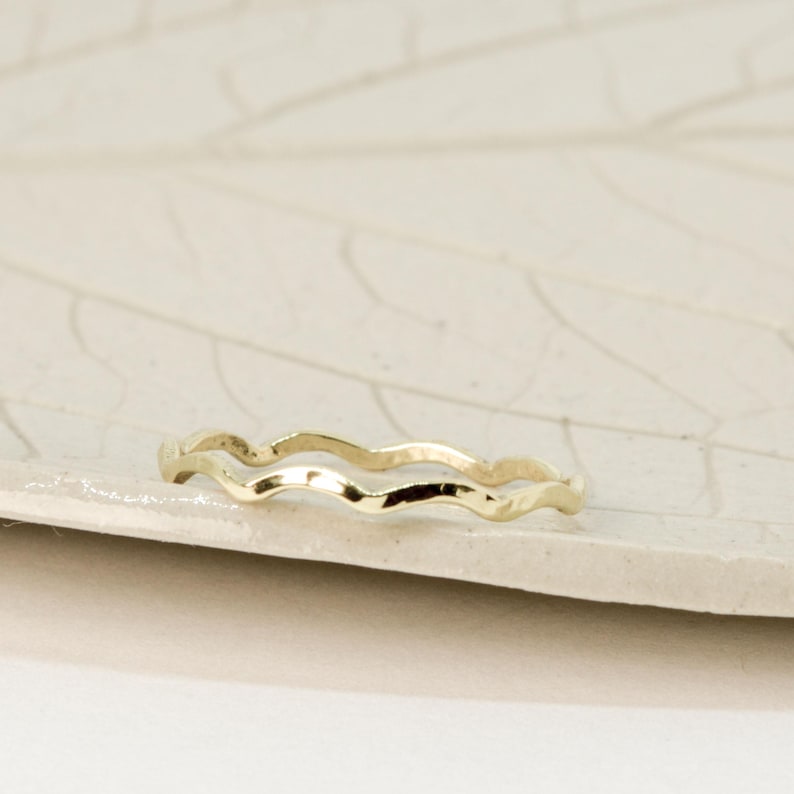 May include: A thin gold ring with a wavy design. The ring is simple and delicate.