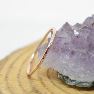 Könnte beinhalten: Ein dünner, gehämmerter Roségoldring, der auf einem Amethyst-Kristallhaufen liegt.