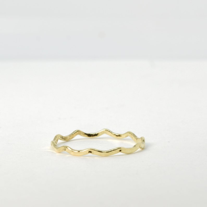 May include: A thin gold ring with a wavy, uneven edge.