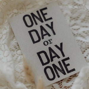 Postkarte "One day or day one?" gestempelter Spruch