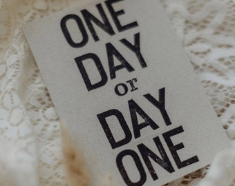 Postcard "One day or day one?" stamped saying
