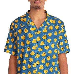 May include: A blue short-sleeved button-down shirt with a yellow rubber ducky pattern.