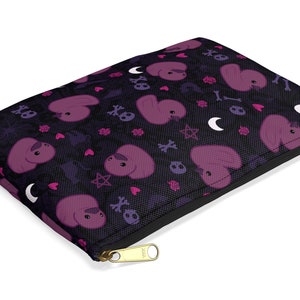 Op de afbeelding: Een zwarte ritszak met een herhalend patroon van roze cartoondieren, harten, sterren, schedels en halve manen.