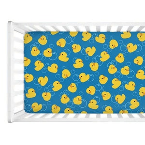 May include: A blue crib sheet with a pattern of yellow rubber duckies and white bubbles.