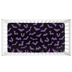 May include: A purple and black crib sheet with a bat pattern.