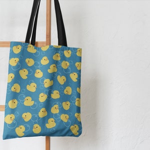 May include: A blue tote bag with a pattern of yellow rubber duckies and white bubbles.