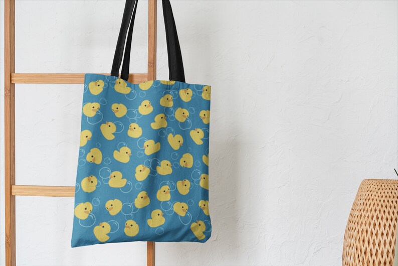 May include: A blue tote bag with a pattern of yellow rubber duckies and white bubbles.