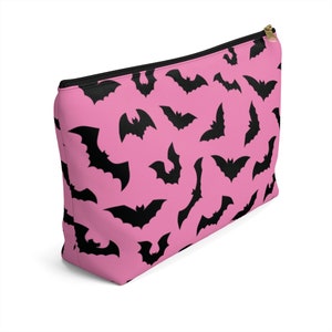 May include: Pink zippered pouch with a black bat pattern.