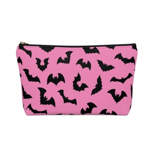 May include: Pink zippered pouch with a black bat pattern.