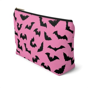 May include: Pink zippered makeup bag with a black bat pattern.