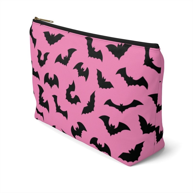 May include: Pink zippered makeup bag with a black bat pattern.