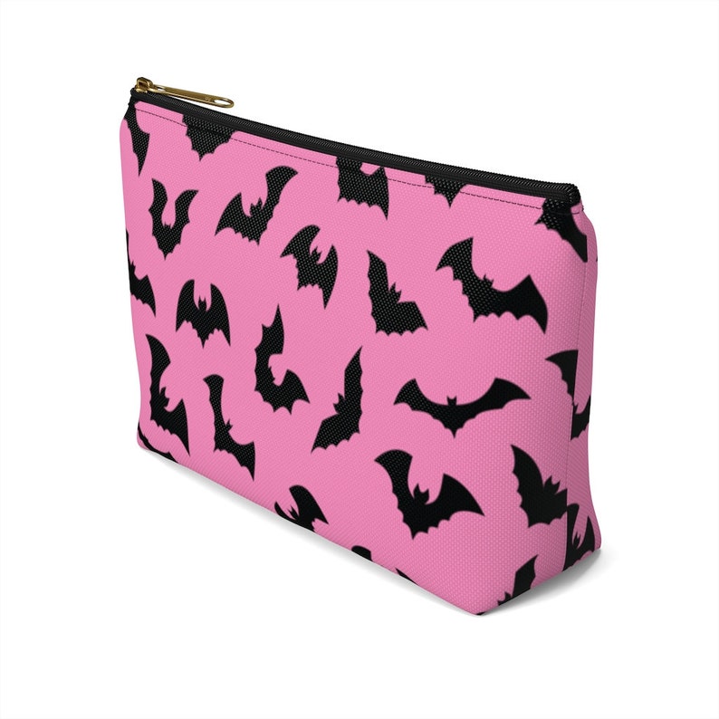 May include: Pink zippered makeup bag with a black bat pattern.