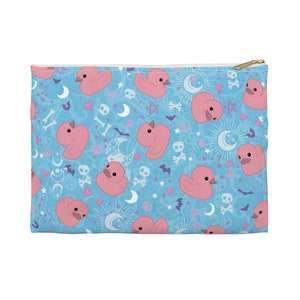 Op de afbeelding: Een blauwe ritszak met een herhalend patroon van roze rubberen eendjes, sterren, manen en schedels.