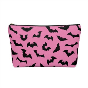 May include: A pink zippered pouch with a black bat pattern.
