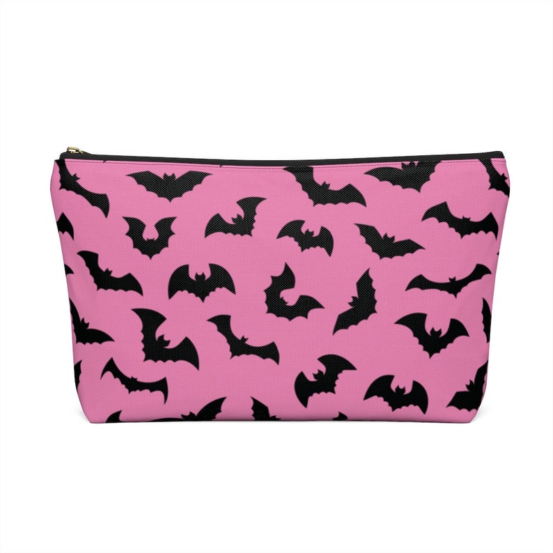 May include: A pink zippered pouch with a black bat pattern.