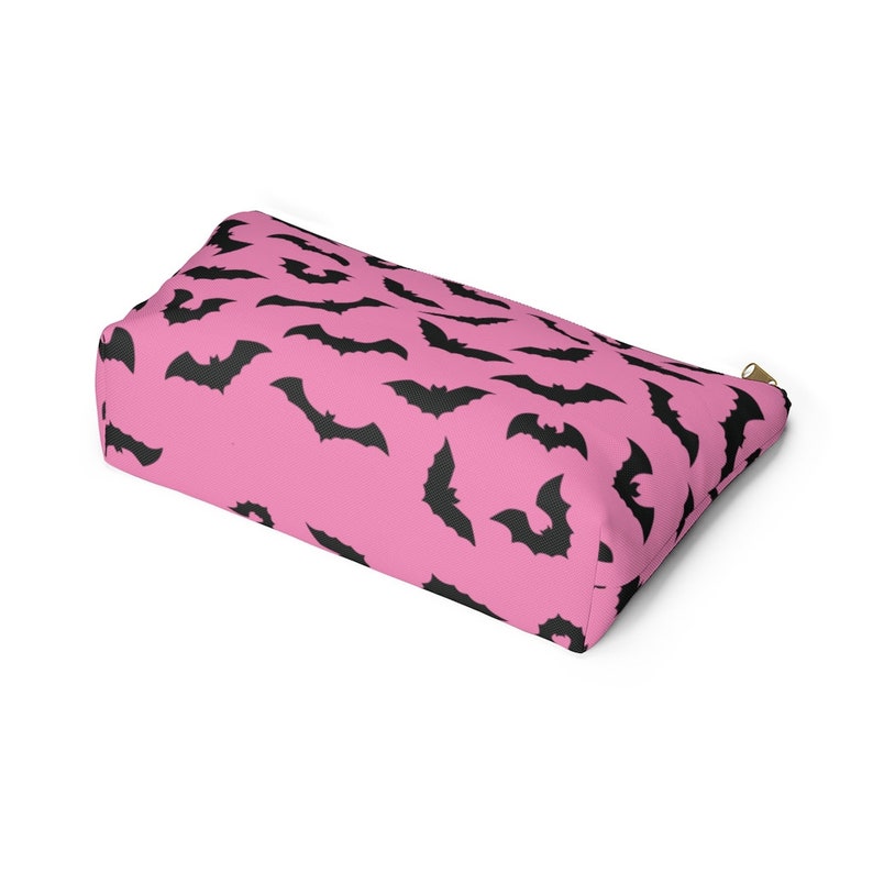 May include: Pink zippered pouch with a black bat pattern.